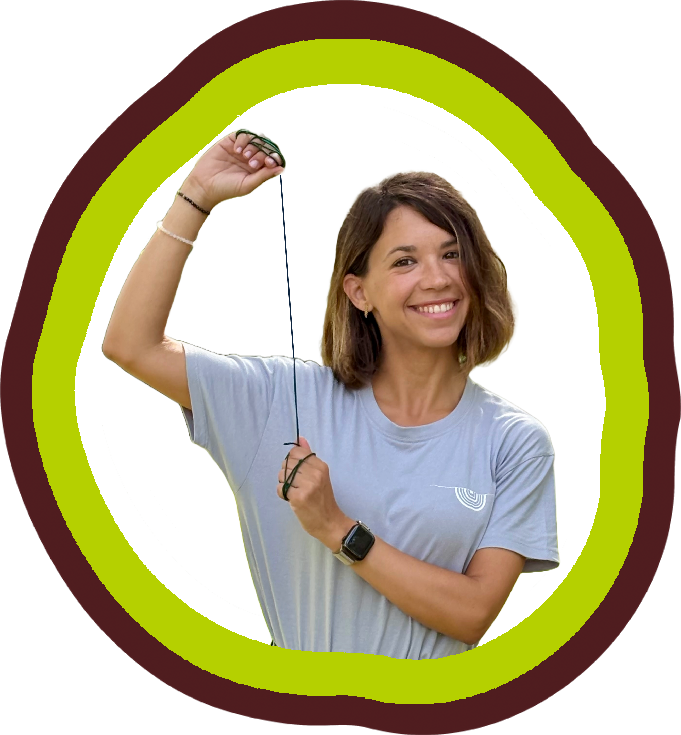 Jove amb una samarreta gris somrient mentre sosté un objecte amb una mà, envoltada per un disseny de fons verd i marró.